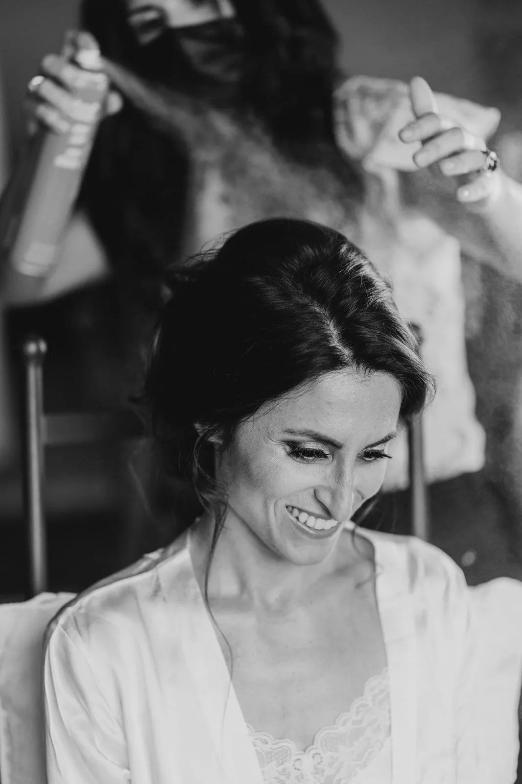 Giulia smiling while her hair is done, in black and white