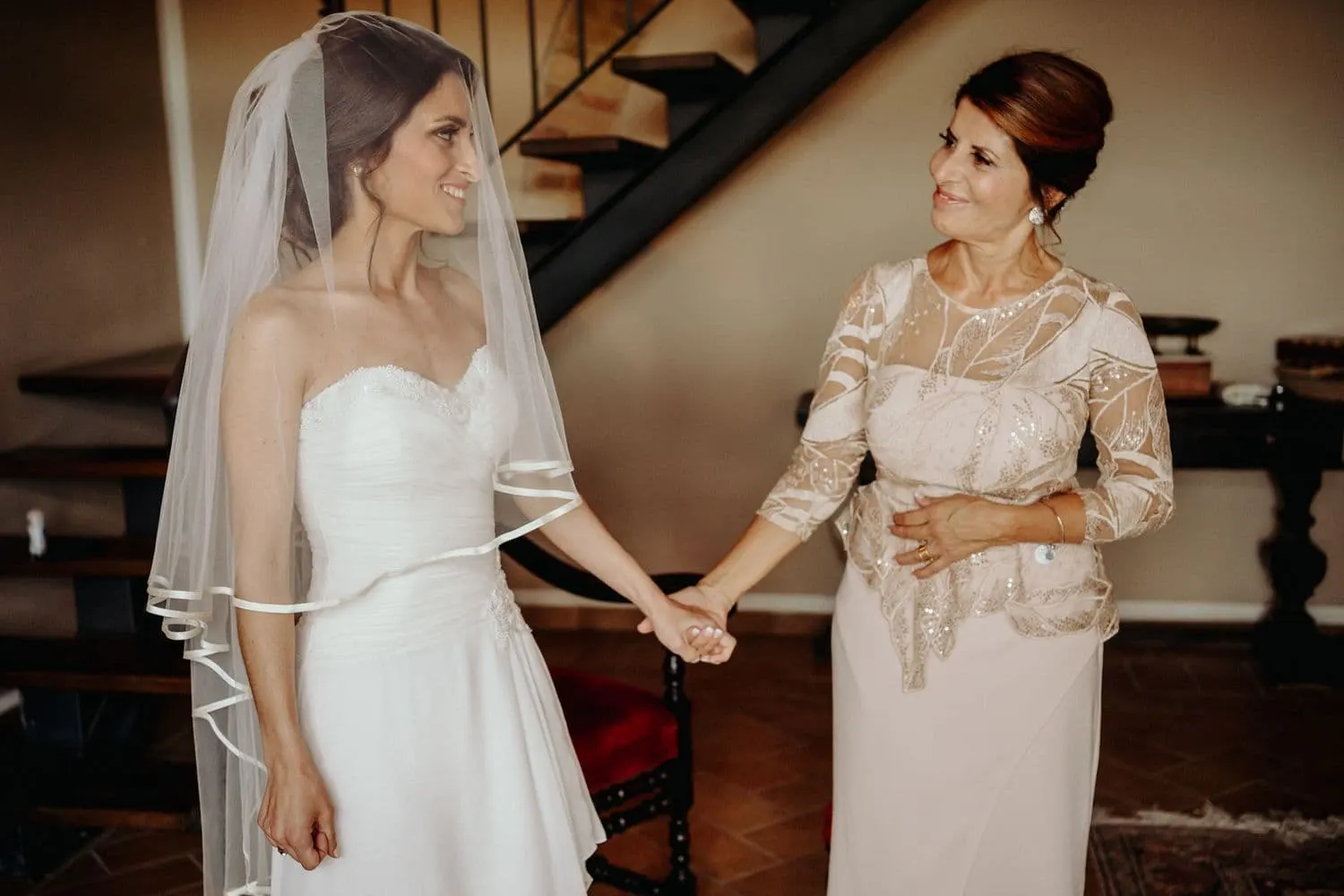 Giulia in her veil holding the hand of a woman in a lace dress before the ceremony