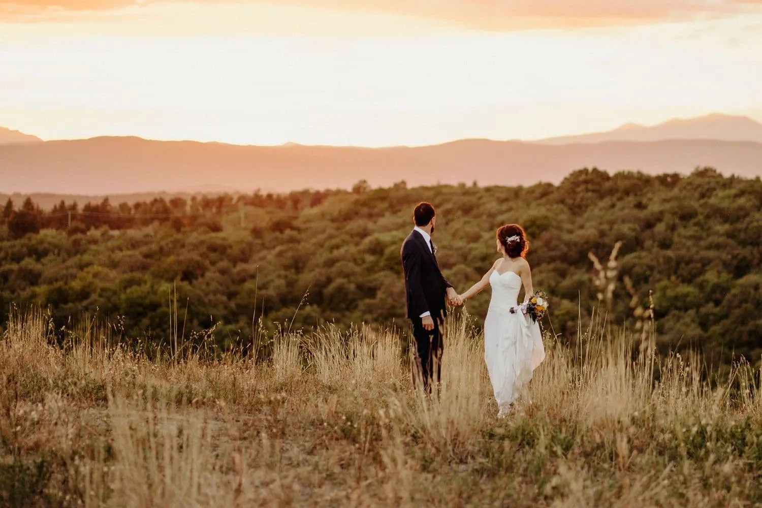 Giulia and Francesco small in the landscape, with the hills on the horizon at sunset